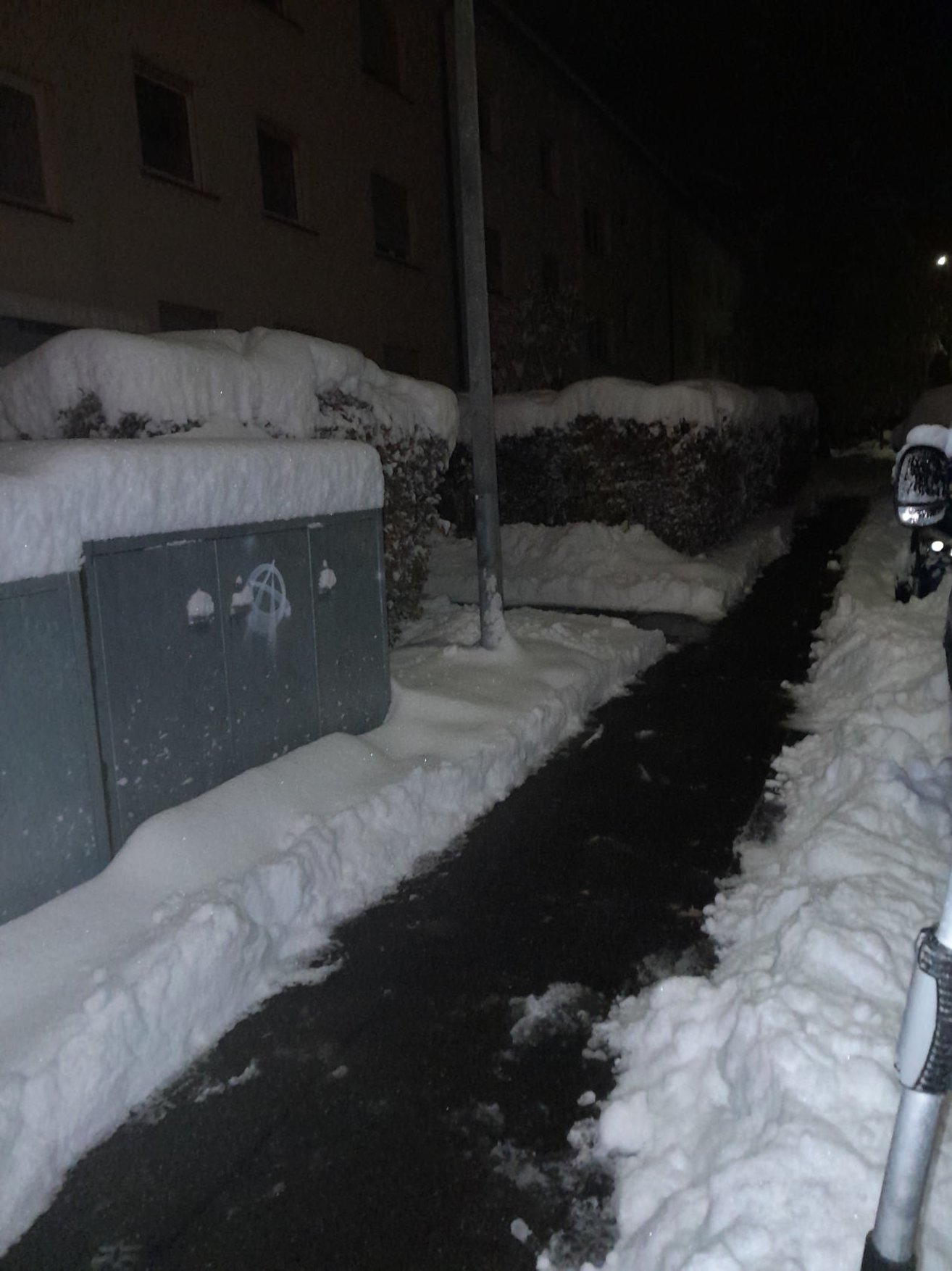 Geräumter Gehweg zwischen verschneiten Grundstücken